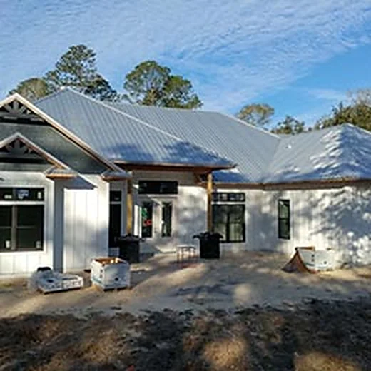 New white board-and-batten home with a gray metal roof and gabled entry