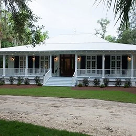 White porch home with a metal roof and wide front steps set back on a green lawn