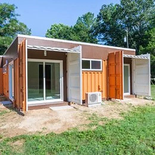 Shipping-container home with wood-clad walls, sliding glass doors and fold-out steel shutters