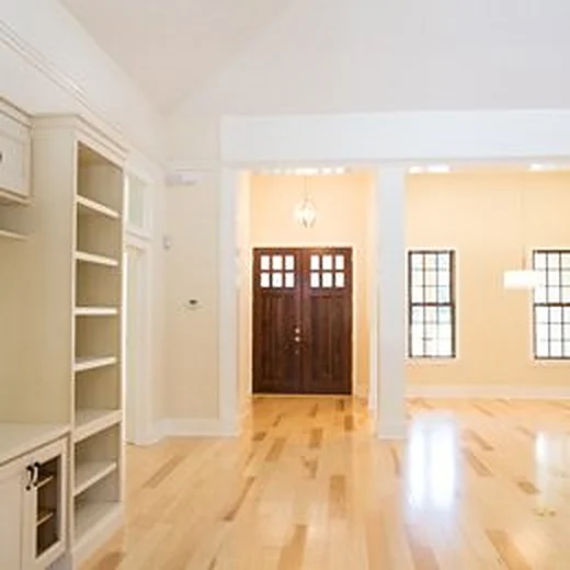Bright foyer with light wood floors, built-in shelving and double wood entry doors