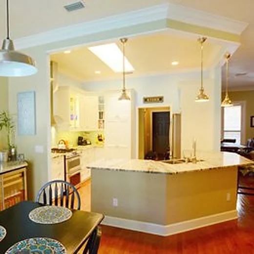 Remodeled kitchen with a granite peninsula, cream cabinets, skylight and pendant lights