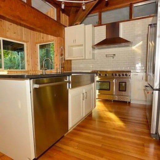 Kitchen with wood-paneled walls and ceiling, subway tile, a pro range and stainless dishwasher